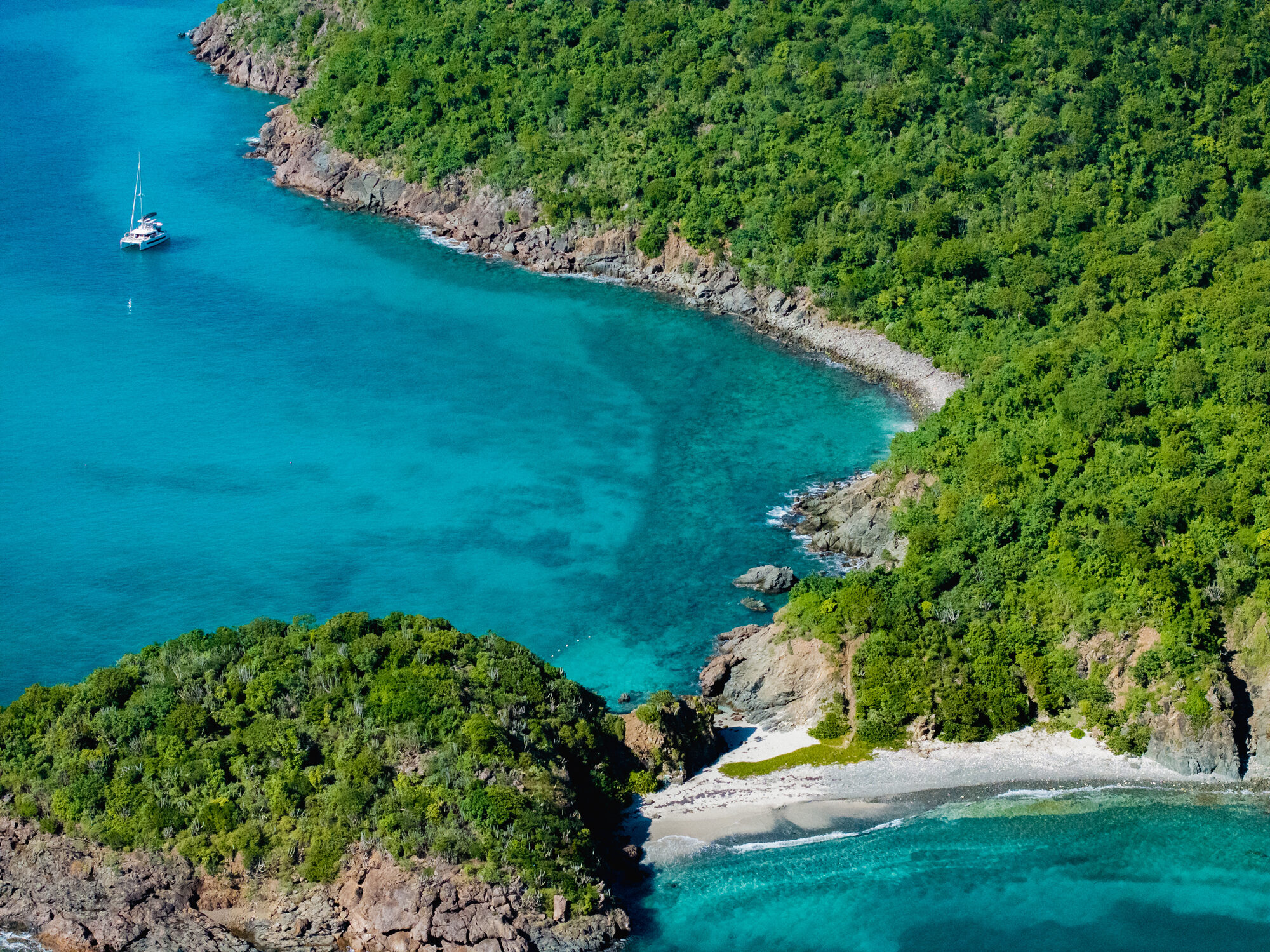 A luxury crewed yacht cruising turquoise waters with lush island shores in the background - Horizon Luxury Crewed