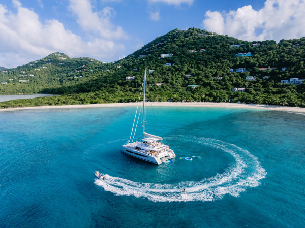 A luxury yacht anchored in stunning blue waters with a speedboat tender circling alongside - Horizon Luxury Crewed