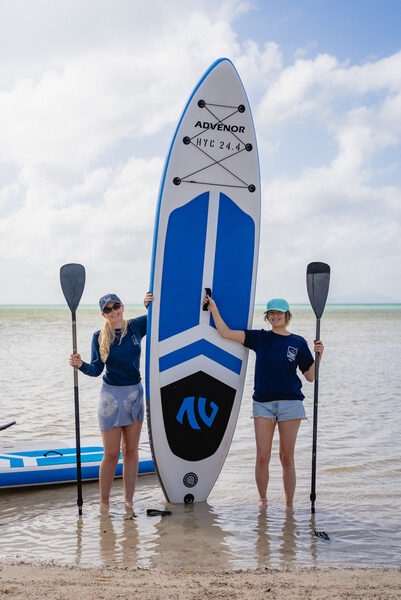 Two Horizon Luxury Crewed crew members holding a paddleboard ready for guests to enjoy on the water - Horizon Luxury Crewed